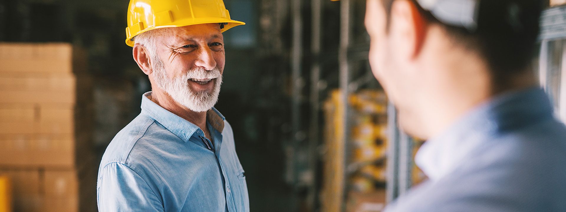 A smiling man in a construction helmet shakes hands with a man